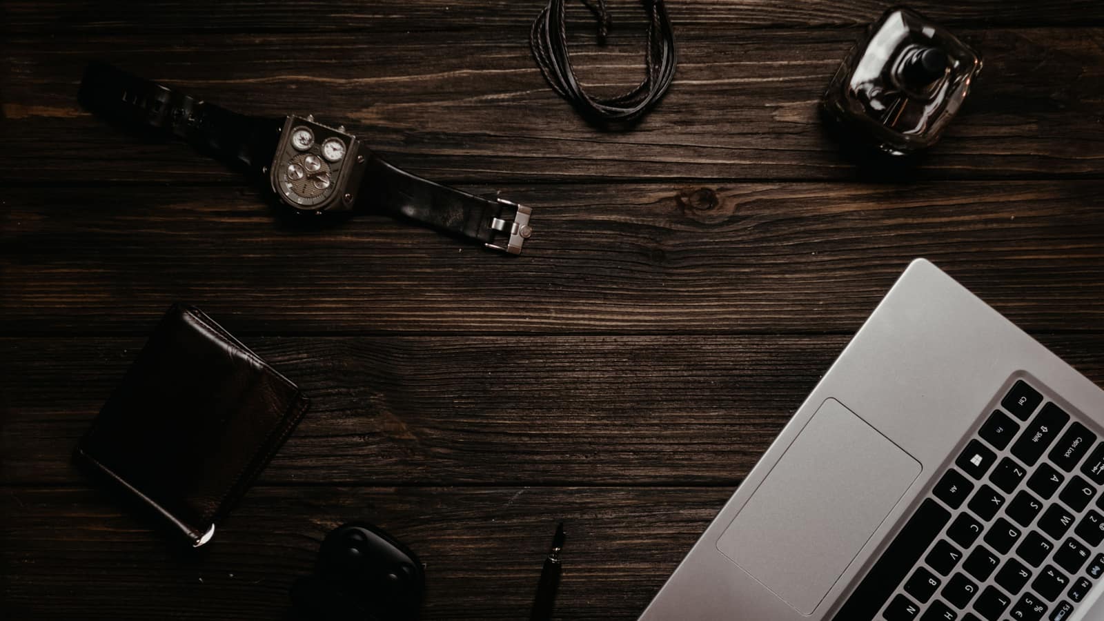 Flat lay of men's everyday accessories including a watch and wallet