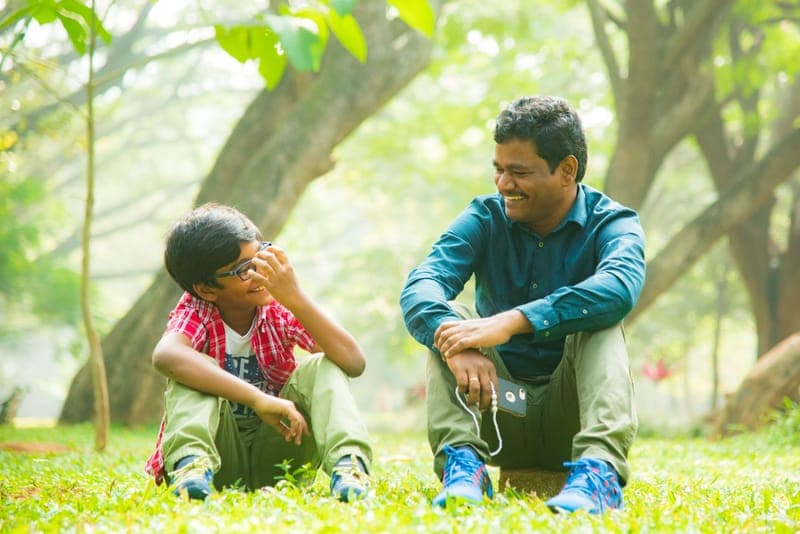 A father and his adult child laughing together outdoors